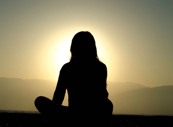 silhouette of lady meditating at sunset
